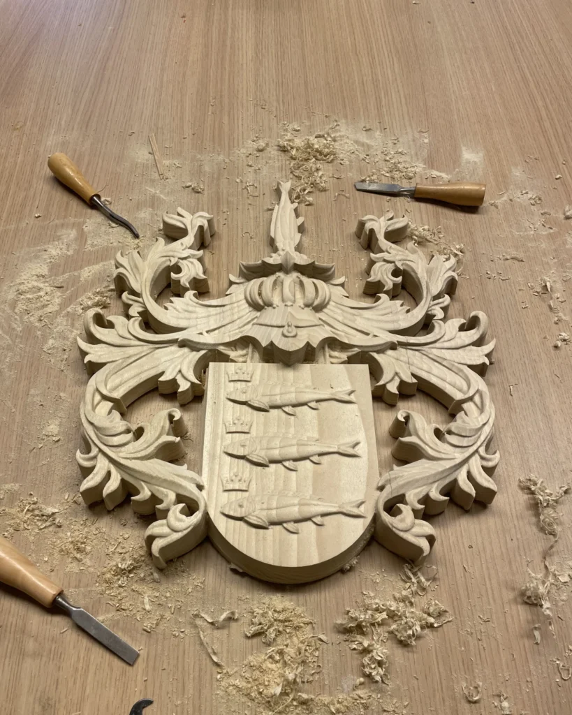 Wooden coat of arms carving in progress with chisel tools on workbench