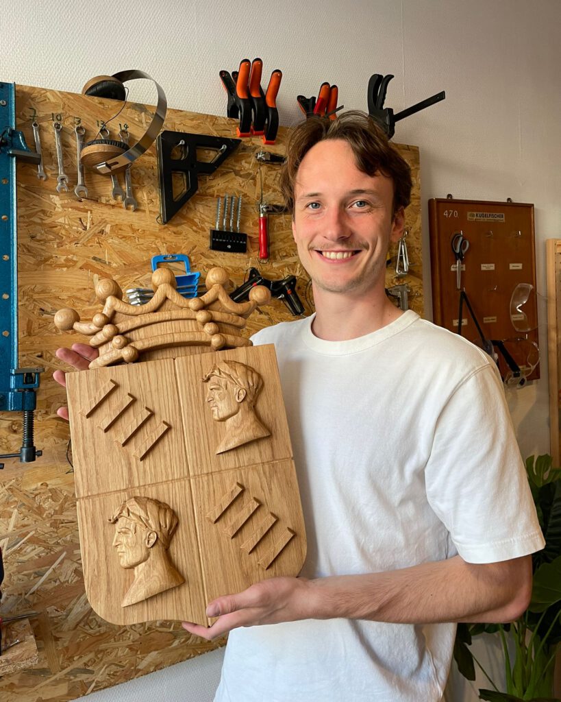 Woodcarver with hand-carved wooden relief portrait sculpture in workshop