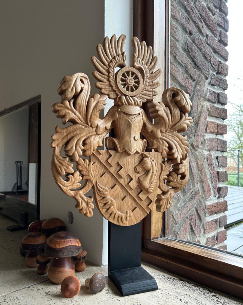 Carved wooden heraldic coat of arms with winged design on display stand